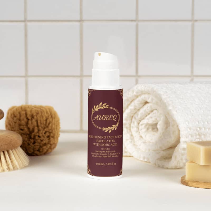 AUREQ Brightening Face&Body Exfoliator with Kojic Acid surrounded by natural sponges and towels in a soothing setting.