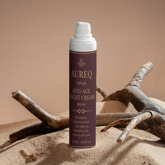 Collagen Anti-Age Night Cream in a stylish bottle on a sandy surface with branches.
