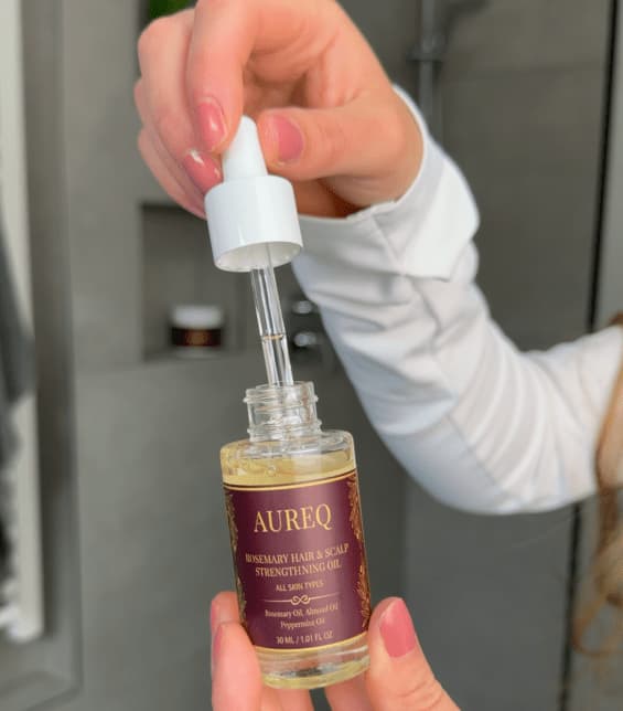 AUREQ rosemary hair oil with a pipette in the hands of a client