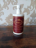 Aureo sensitive scalp shampoo bottle on a wooden surface with decorative wallpaper in the background