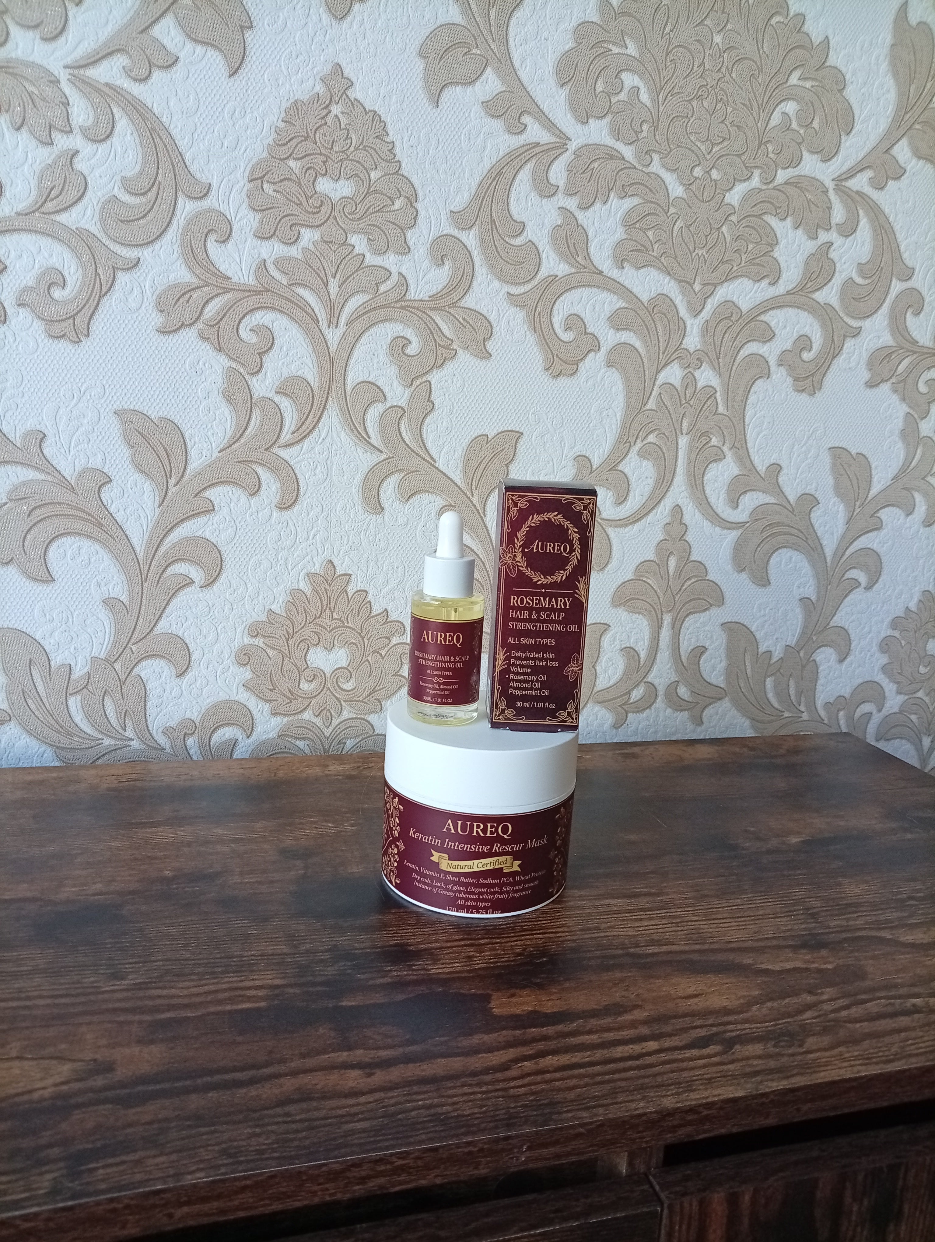 AUREQ products on a wooden surface with decorative wallpaper in the background