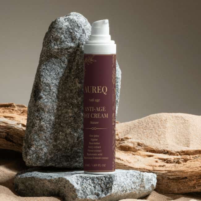 Anti-Age Day Cream in elegant packaging displayed on stone and sand background.