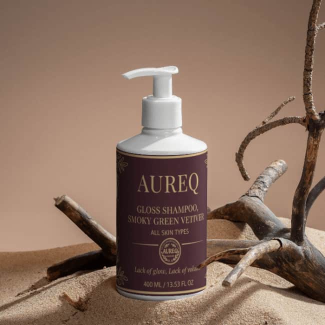 Gloss Shampoo, Smoky Green Vetiver in a stylish bottle on sandy background with natural elements.