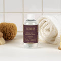 AUREQ Glycolic Acid Exfoliating Toner bottle on a bathroom counter with skincare accessories.